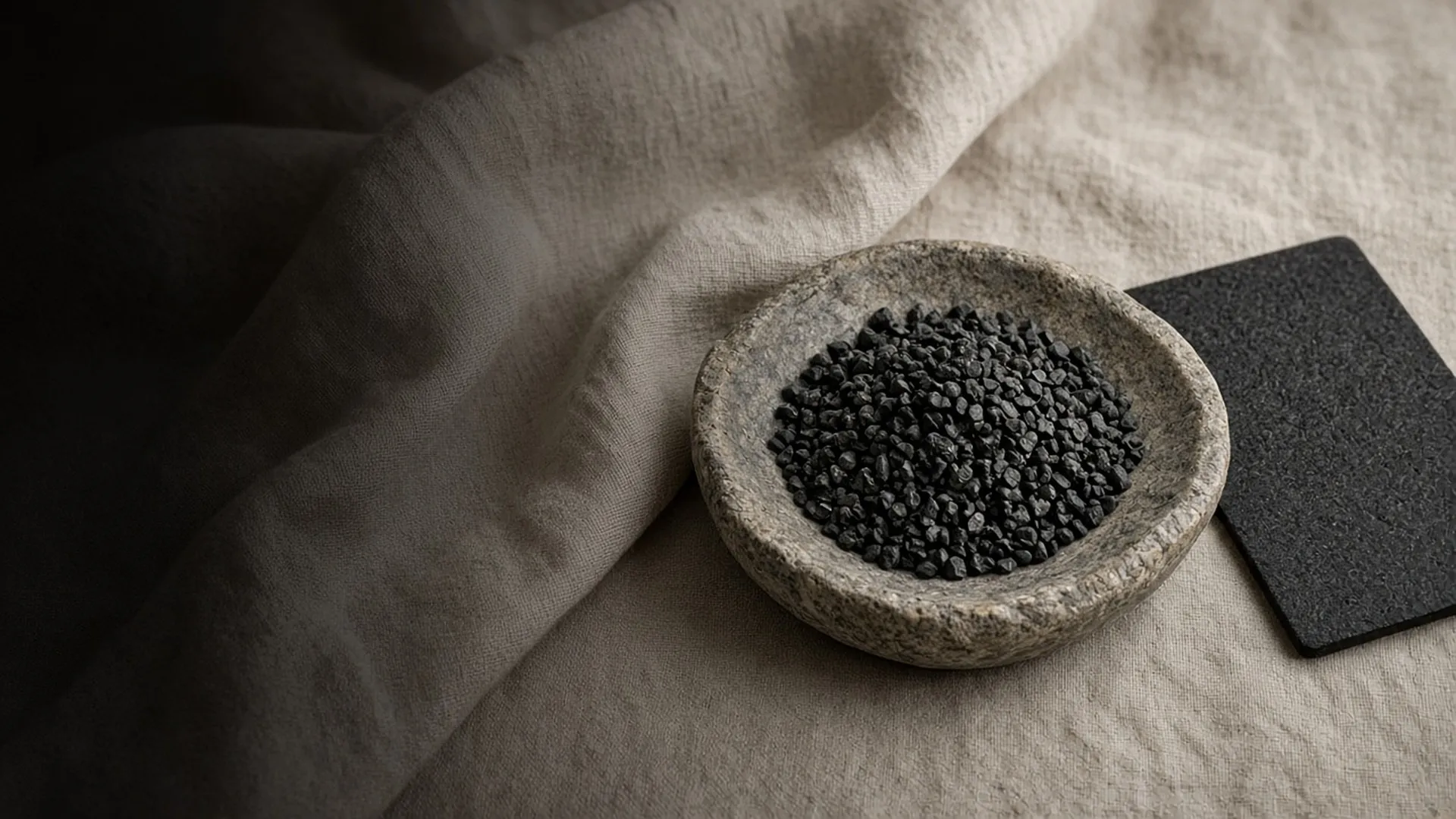 Carbon granules in a stone dish beside a carbon filter sheet