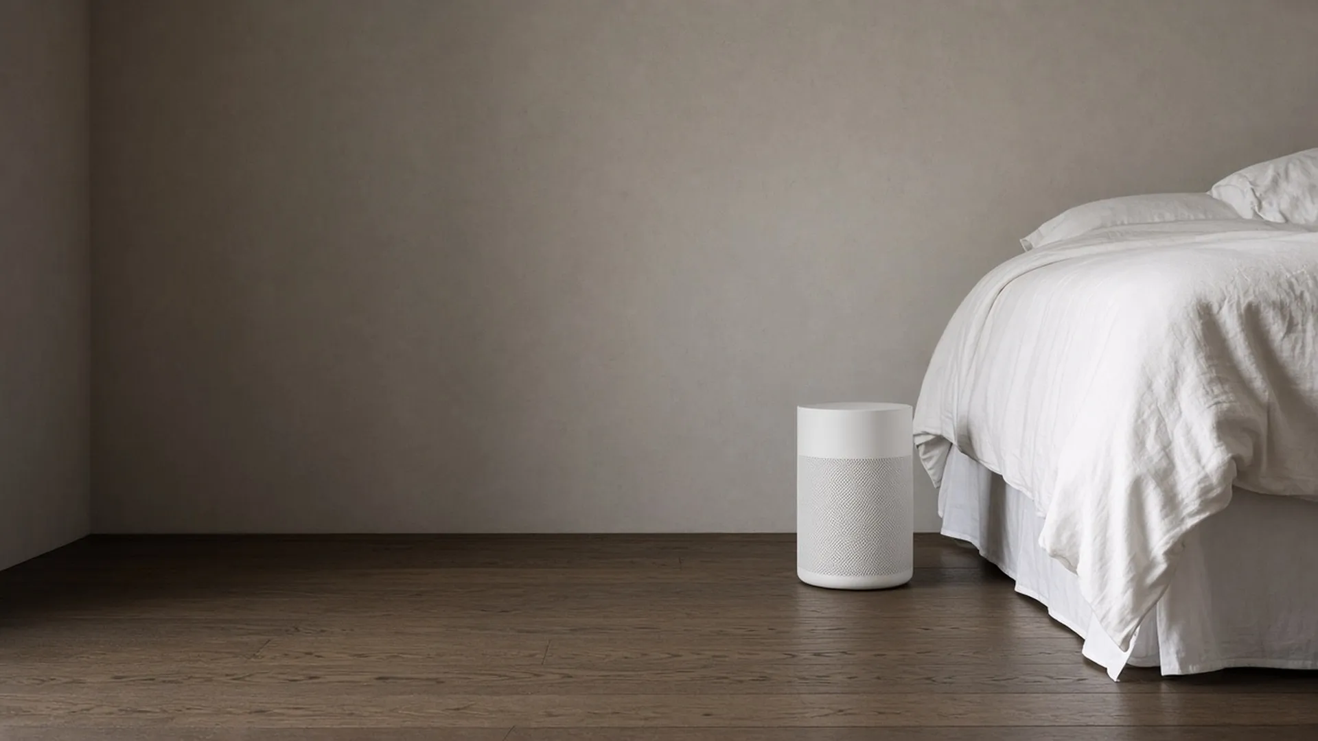 A freshly made bed with a plain air purifier beside it